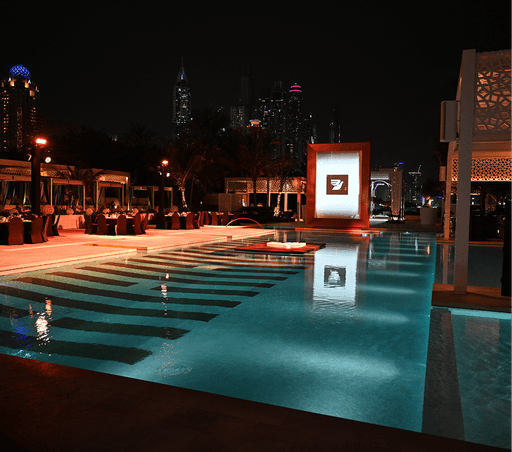 A luxurious outdoor pool area is illuminated at night.